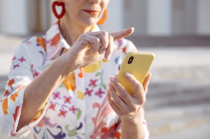 Äldre kvinna scrollar på telefon