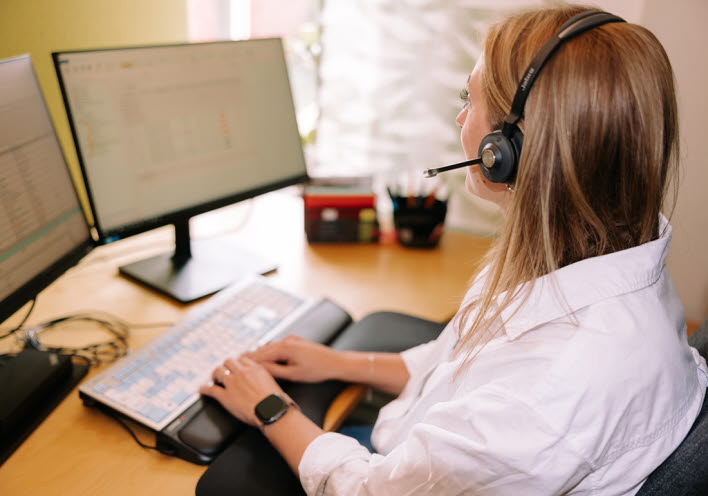 telefonist med headset sitter vid datorn 