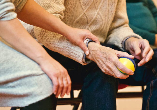 Äldre hand håller i boll och yngre hand stöttar.