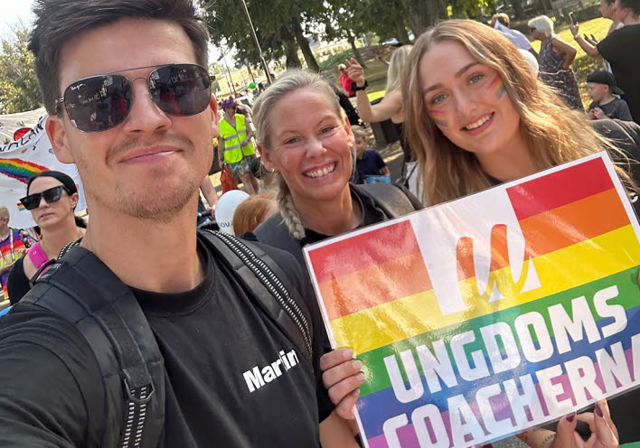 Tre personer går i pridetåget.