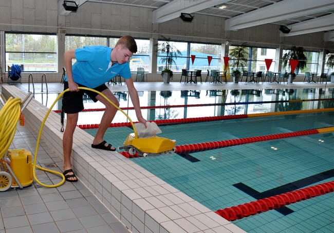 Adam sänker med dammsugaren i bassängen.