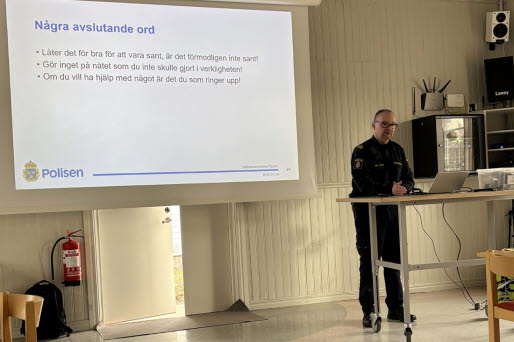 En polis står på scen och håller föredrag. I bakgrunden syns en Powerpoint-presentation.