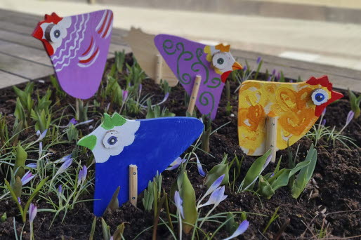 Små påskkycklingar i trä uppställda i en blomkruka ute.