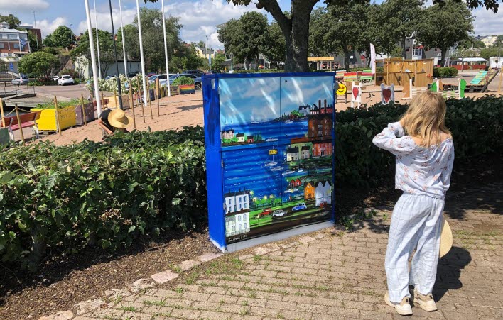 Elskåp som är målat som hamnen. En person tittar på det.