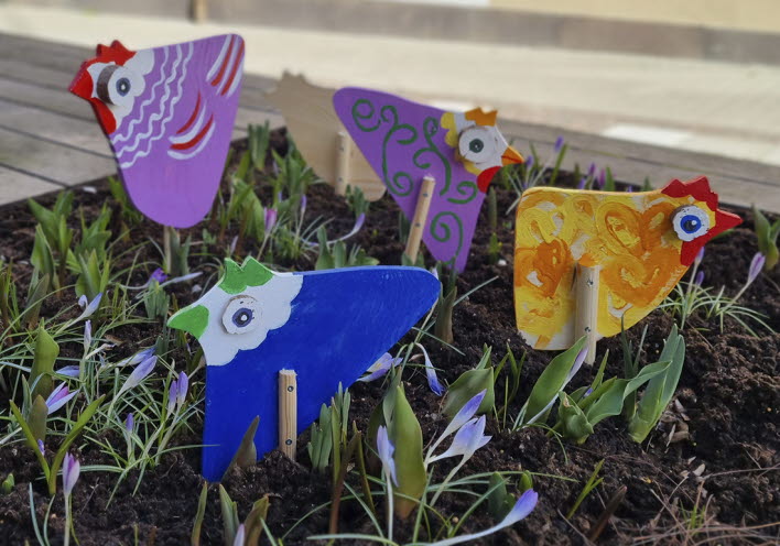 Små påskkycklingar i trä uppställda i en blomkruka ute.