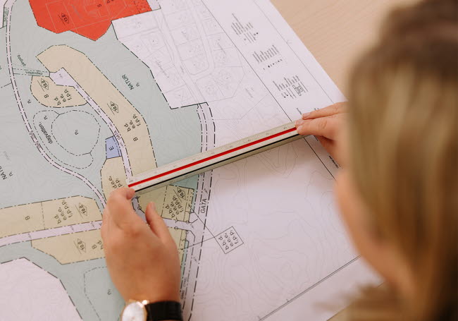 En person mäter avstånd på en planritning.