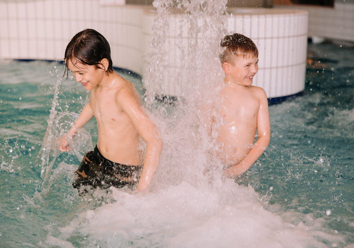 Två pojkar badar i simbassängen.