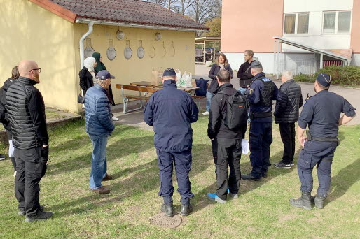 En grupp  människor samtalar utanför ett flerbostadshus.