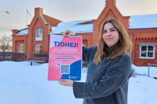 Frida Bobeck håller upp affisch framför stadshuset