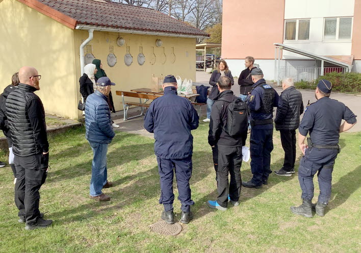 En grupp  människor samtalar utanför ett flerbostadshus.