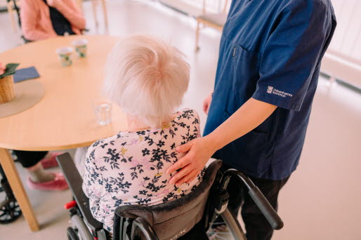 undersköterska håller handen på äldre kvinnas rygg 