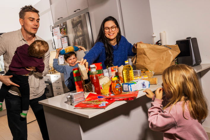 Familj samlade runt bänk med matvaror