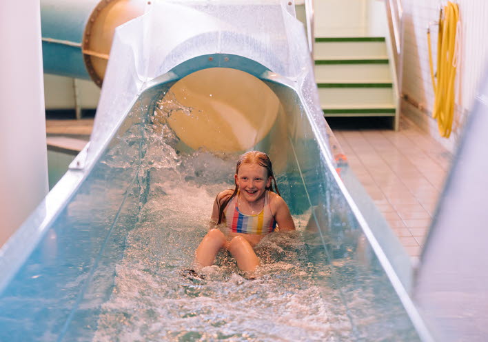 En flicka åker nedfäör en vattenrutschkana.