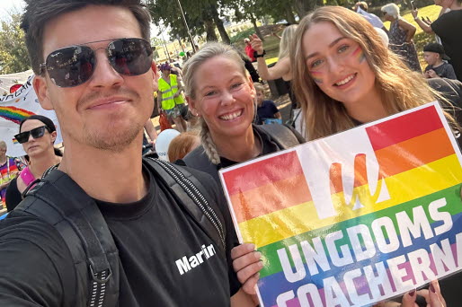 Tre personer går i pridetåget.