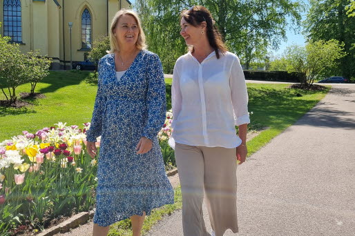 Två kvinnor promenerar i stadsparken