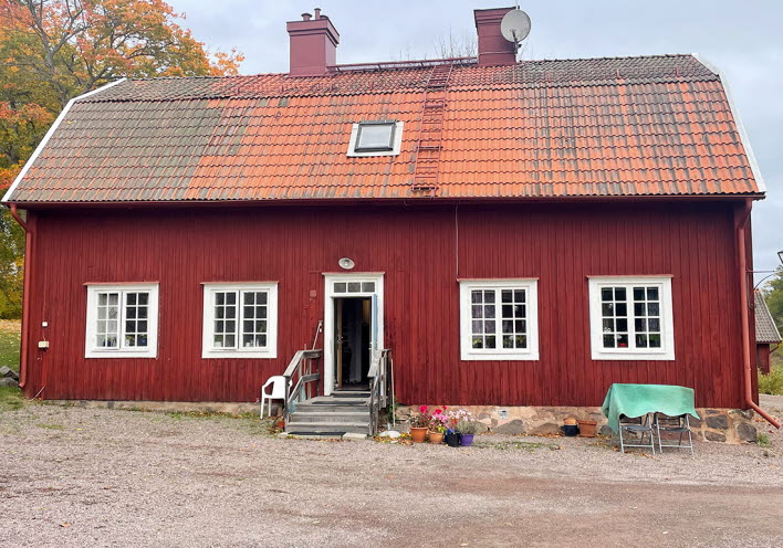 Framsidan av huset. Ett rött trähus med röd tegel.