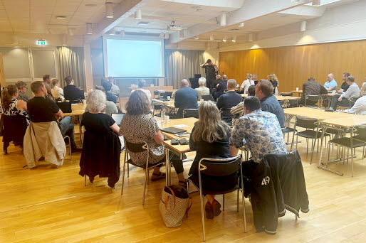 En stor föreläsning med människor sittandes i grupper.