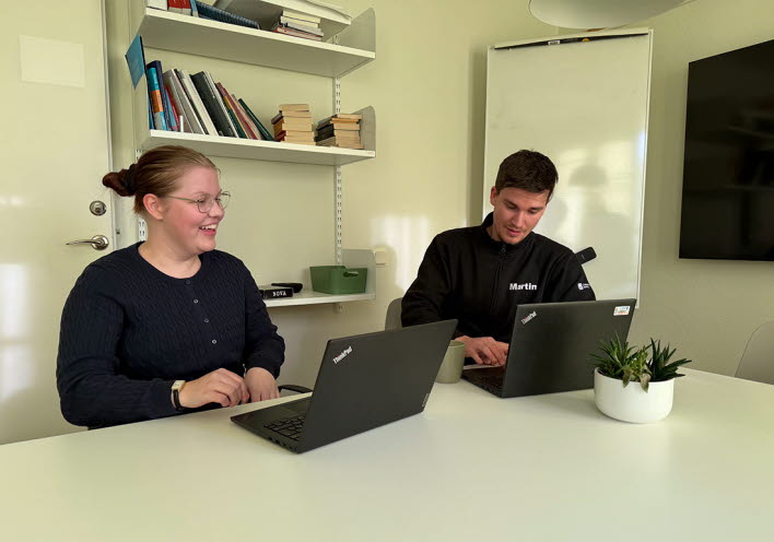 En tjej och en kille sitter vid ett bord med datorer framför sig.