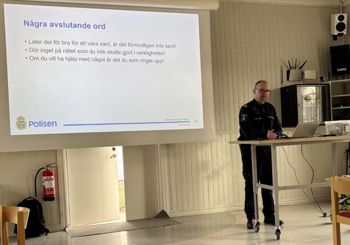 En polis står på scen och håller föredrag. I bakgrunden syns en Powerpoint-presentation.