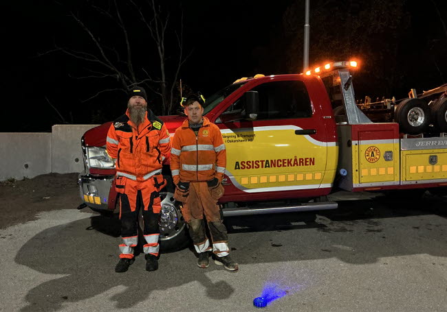 Två killar från Assistanskåren står framför en av sina bilar.
